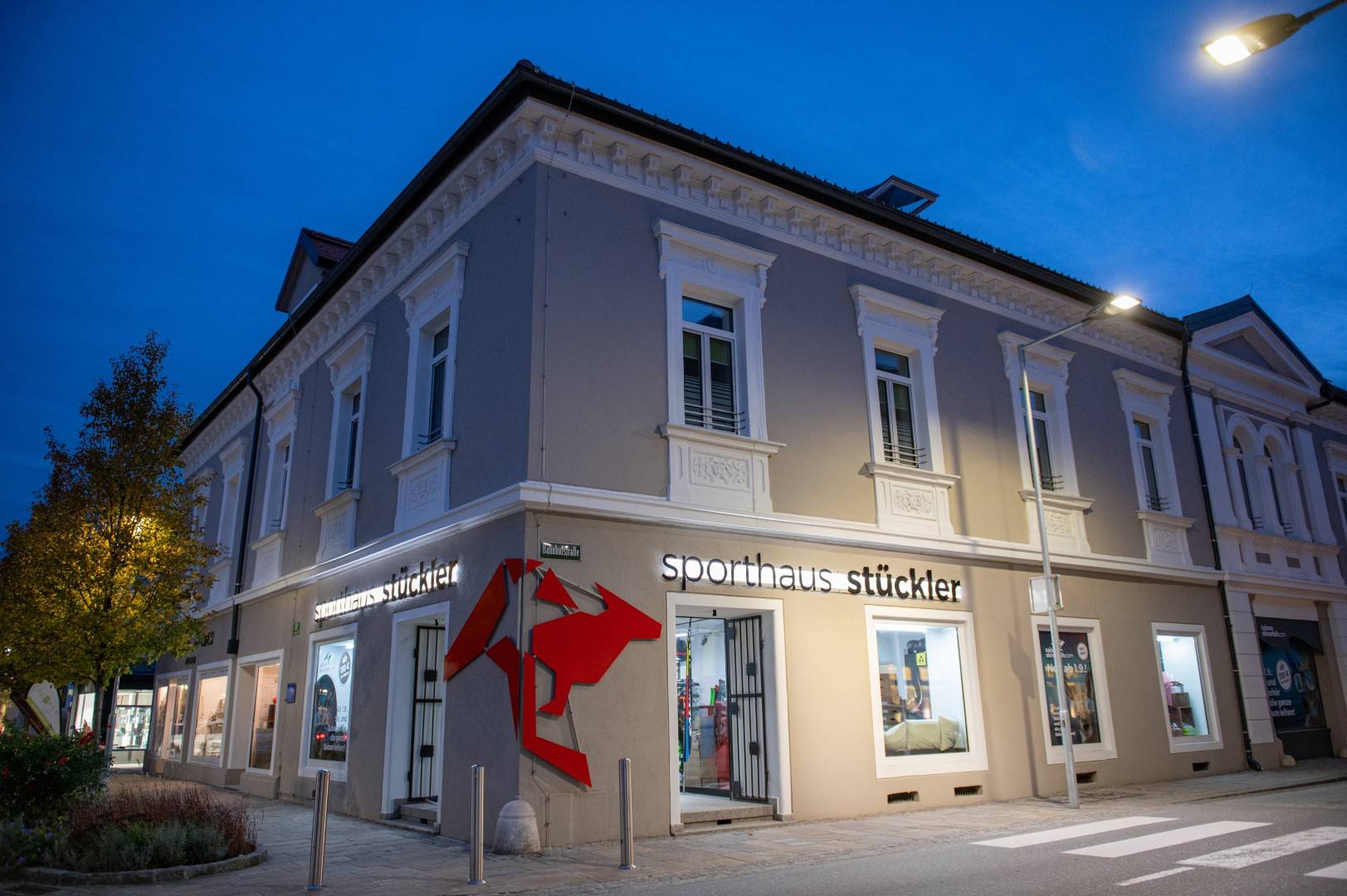 Eckgebäude mit der Aufschrift 'sporthaus stückler' und rotem Logo an der Fassade. Fenster und Eingang sind klar sichtbar.