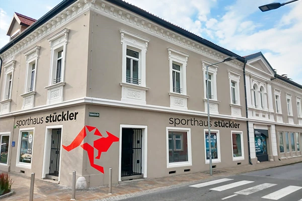 Eckgebäude mit der Aufschrift 'sporthaus stückler' und rotem Logo an der Fassade. Fenster und Eingang sind klar sichtbar.