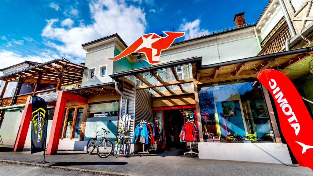 Eingang des Sporthauses mit einem großen Logo und Sportbekleidung in verschiedenen Farben ausgestellt.