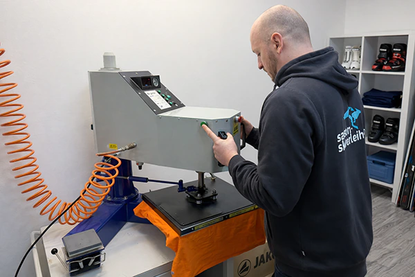 Ein Mann Bedruckt ein orange T-Shirt mit der Textil-Transfairpresse